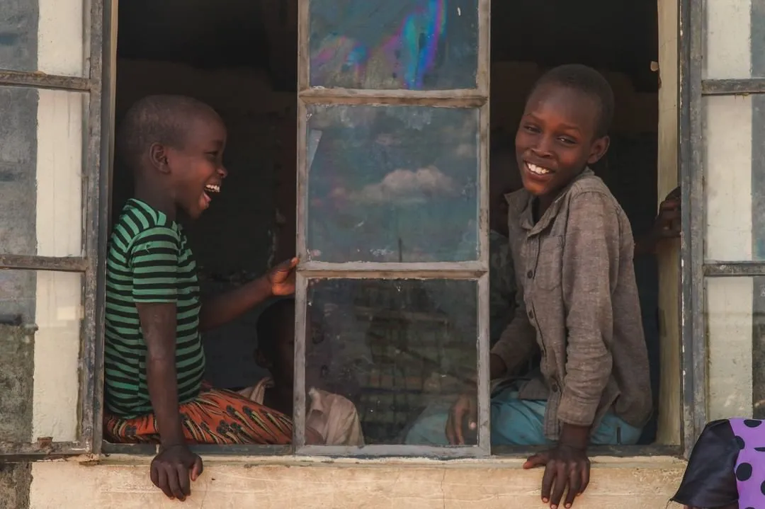 Two happy children sitting in open window in rural Africa
